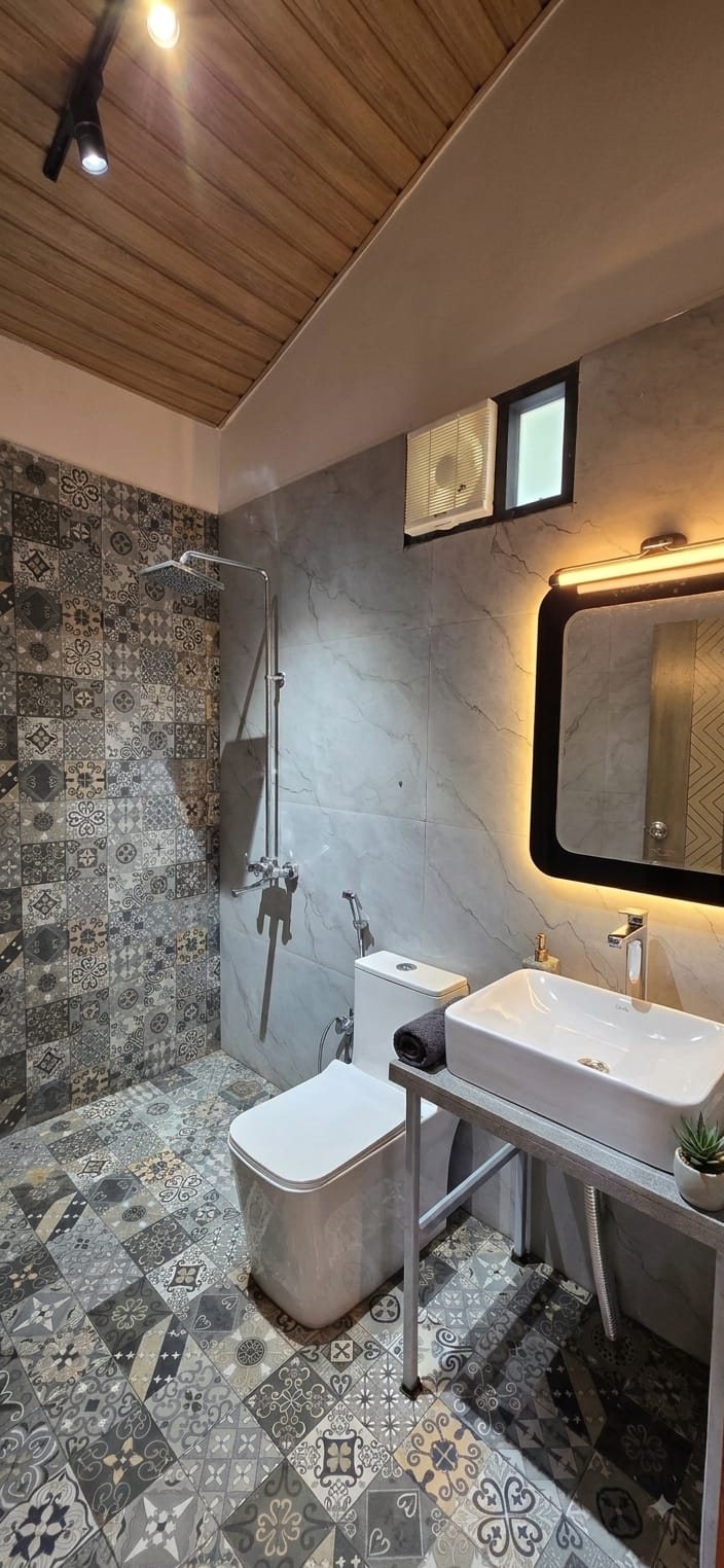 Private bathroom with patterned tiling and a rain shower