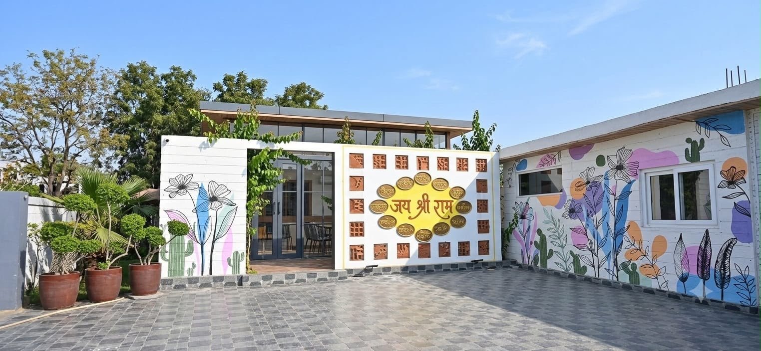 The entrance courtyard at Aanandam by Saryu, with a gold Jai Shree Ram wall and painted botanical murals